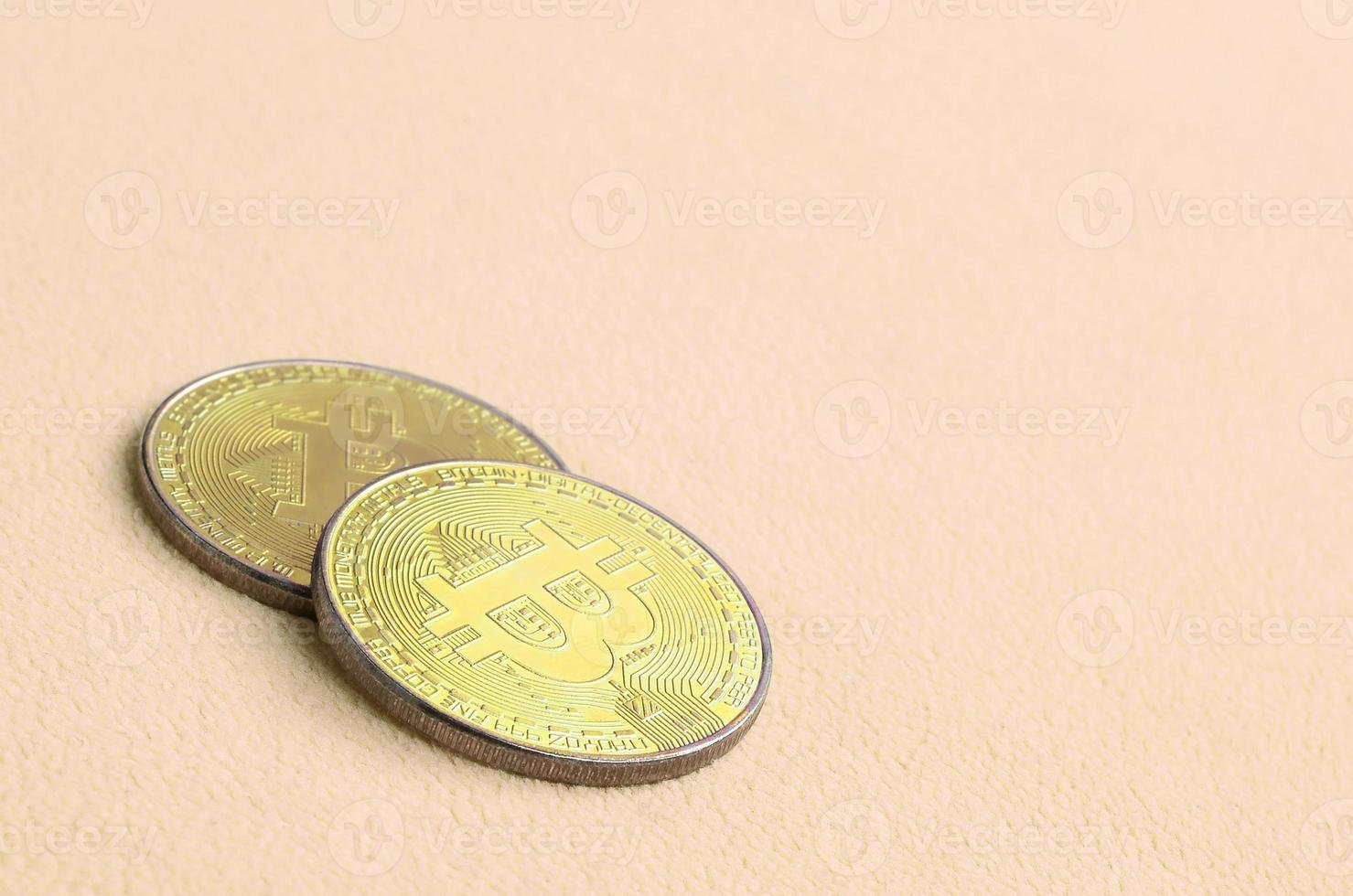 Two golden bitcoins lies on a blanket made of soft and fluffy light orange fleece fabric. Physical visualization of virtual crypto currency photo