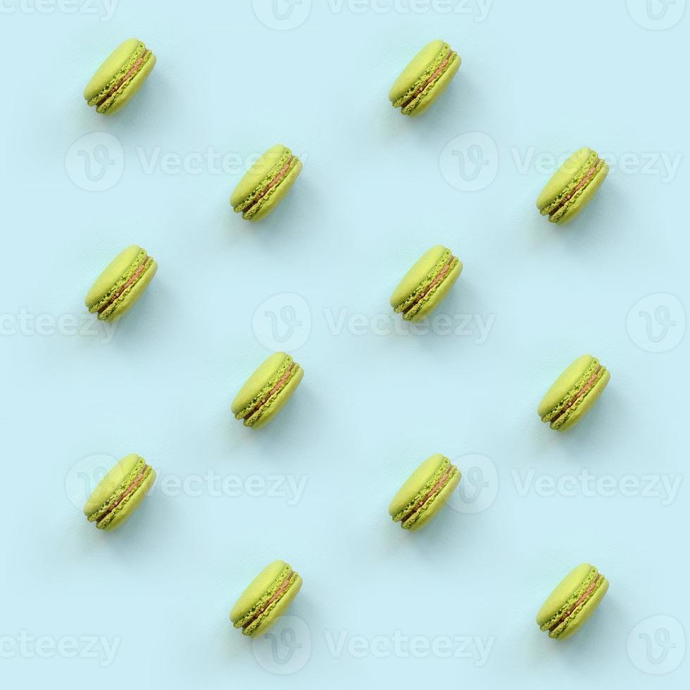 Green dessert cake macaron or macaroon on trendy pastel blue background top view. Flat lay pattern composition photo