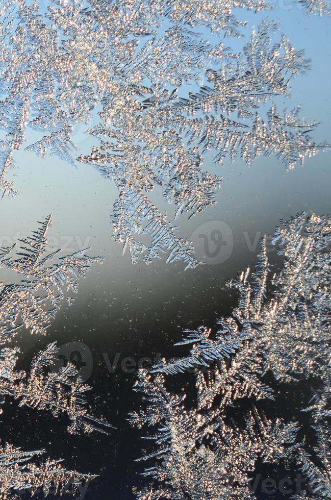 Snowflakes frost rime macro on window glass pane photo