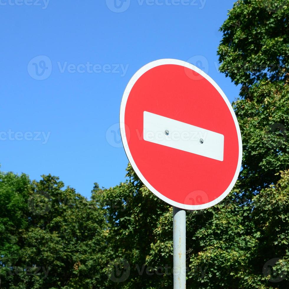 A circular red sign with a white bar indicating NO ENTRY on a grey metal post photo