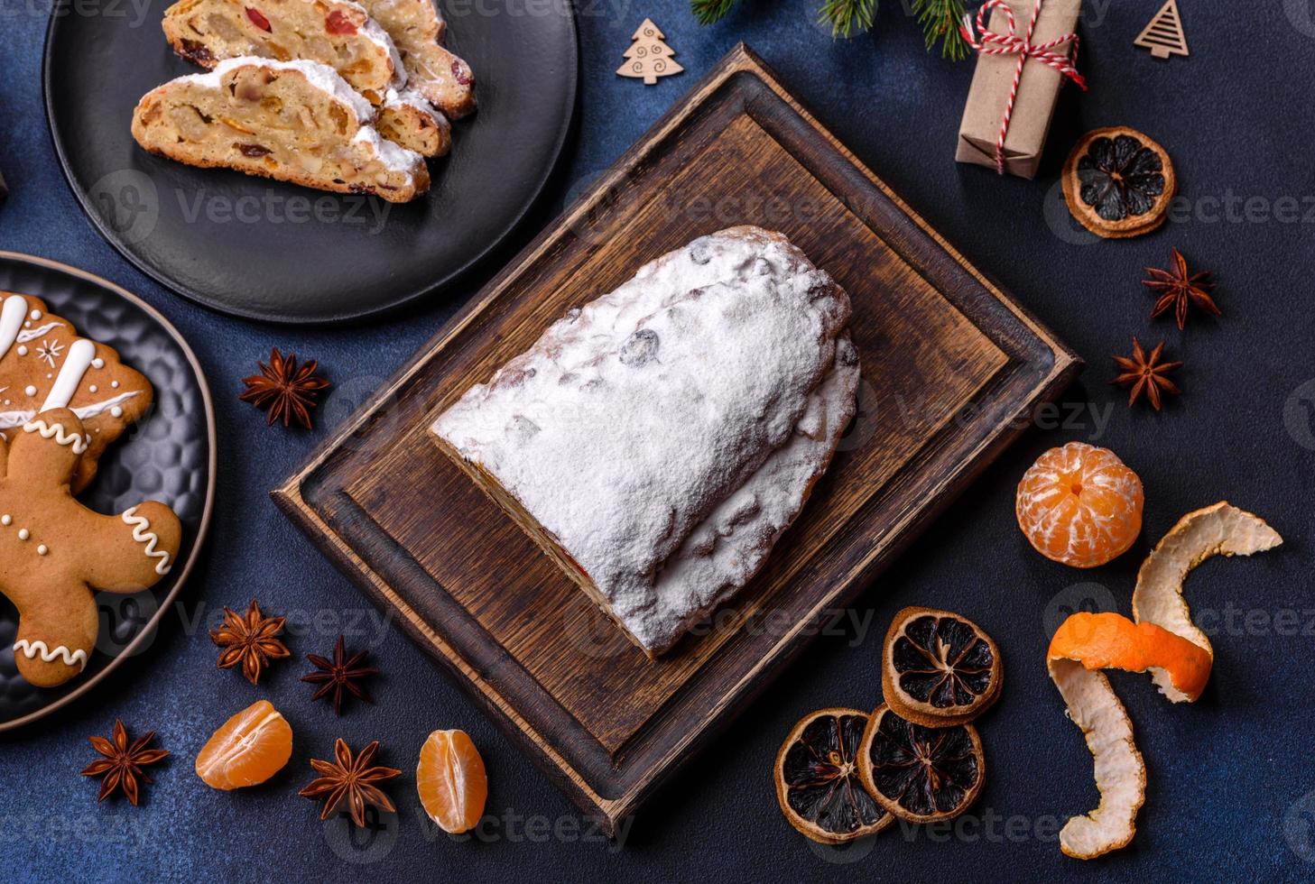 delicioso pastel festivo de año nuevo con frutas confitadas, mazapán y nueces sobre un fondo de hormigón oscuro foto