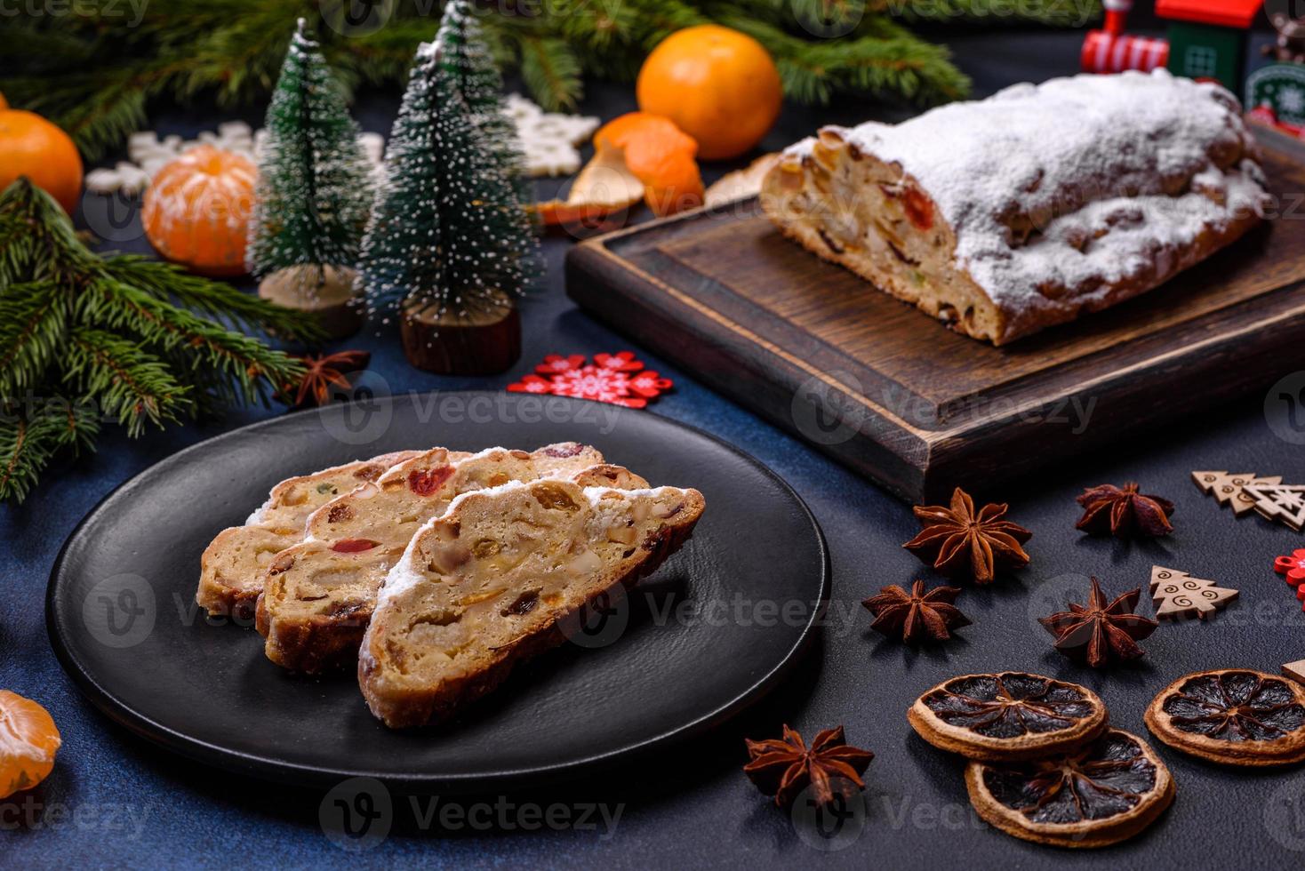 delicioso pastel festivo de año nuevo con frutas confitadas, mazapán y nueces sobre un fondo de hormigón oscuro foto