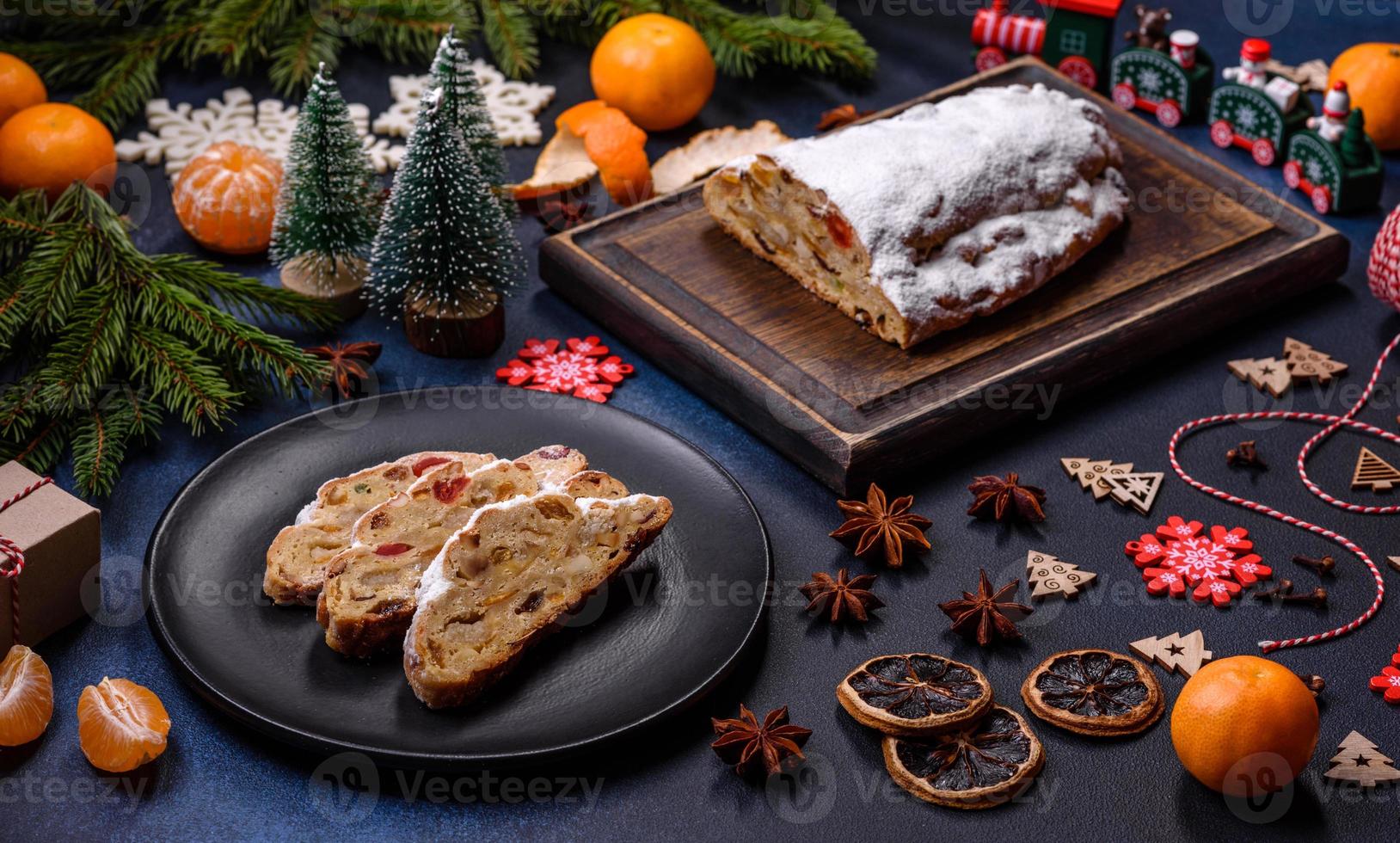 delicioso pastel festivo de año nuevo con frutas confitadas, mazapán y nueces sobre un fondo de hormigón oscuro foto
