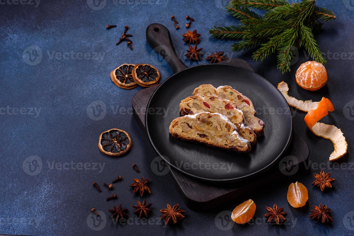 delicioso pastel festivo de año nuevo con frutas confitadas, mazapán y nueces sobre un fondo de hormigón oscuro foto