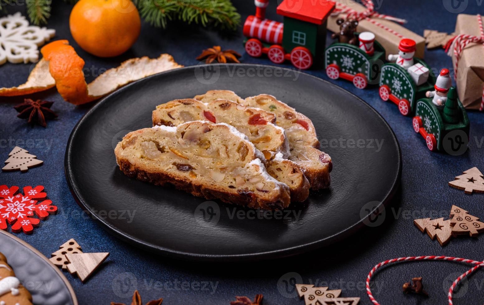 delicioso pastel festivo de año nuevo con frutas confitadas, mazapán y nueces sobre un fondo de hormigón oscuro foto