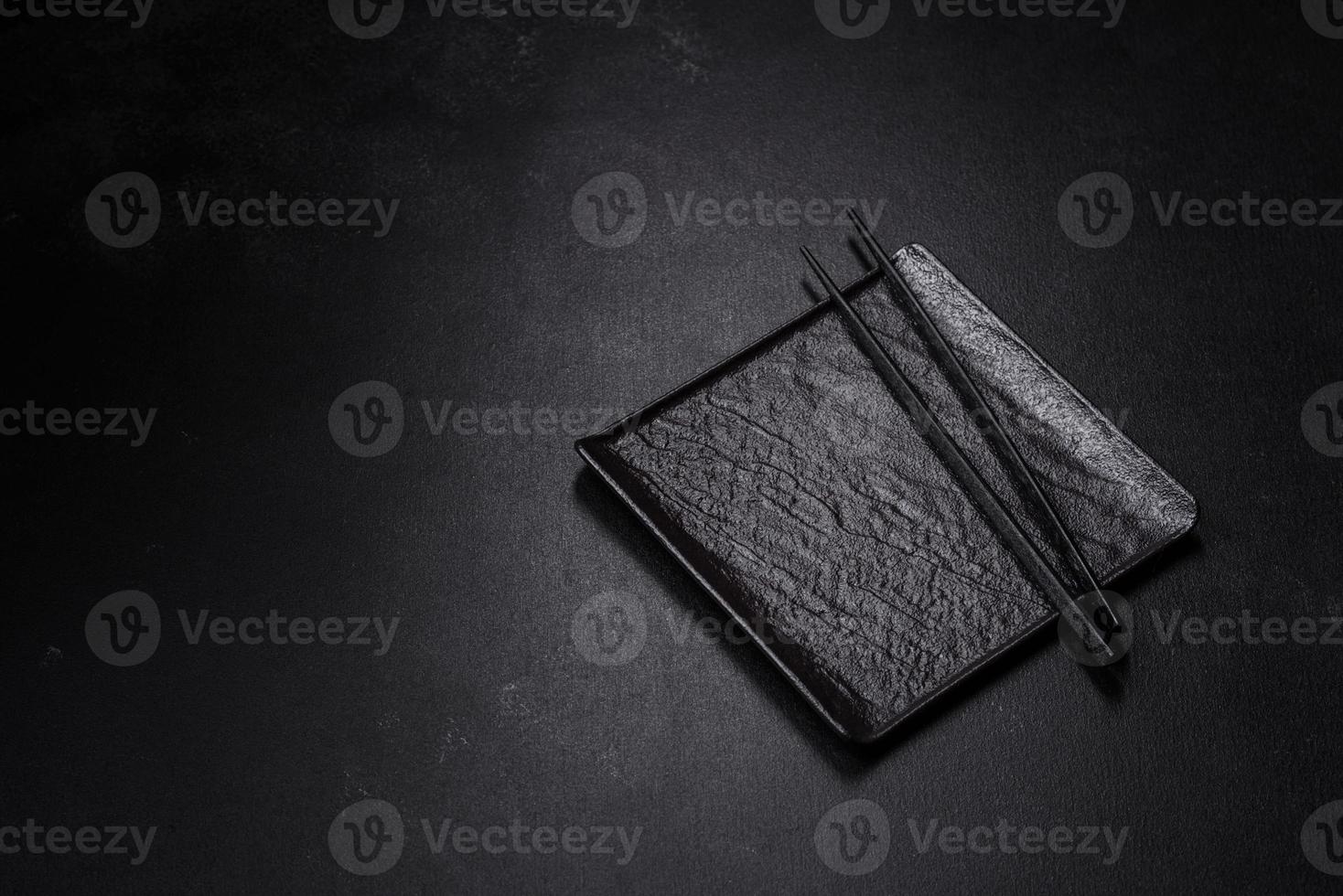 Empty plate with wooden sticks for Asian food on a dark concrete background photo