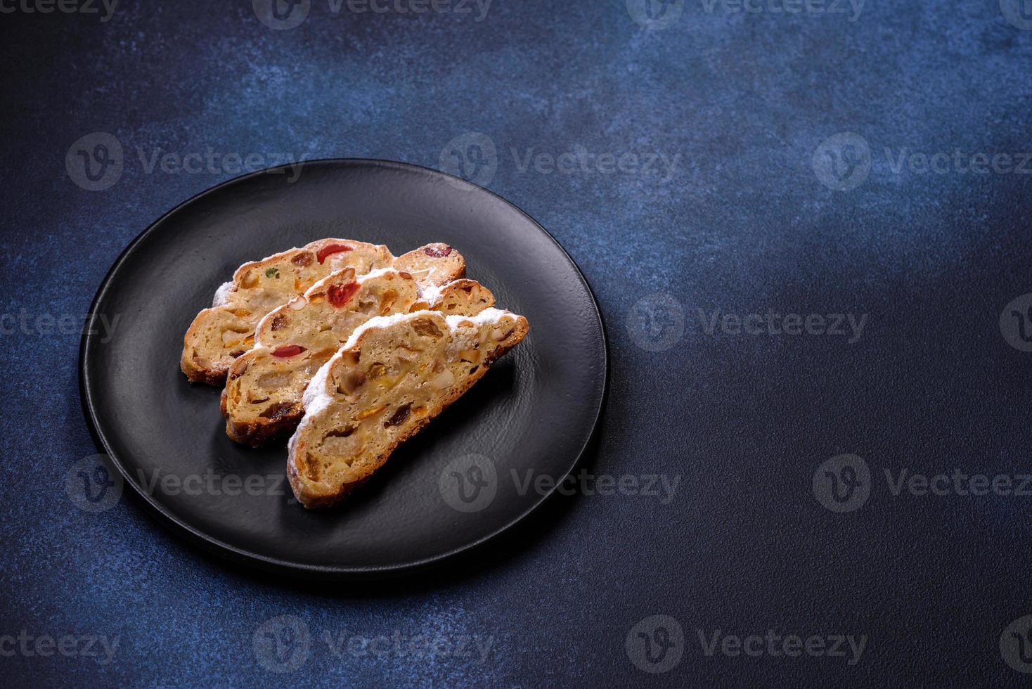 Delicious festive New Year's pie with candied fruits, marzipan and nuts on a dark concrete background photo