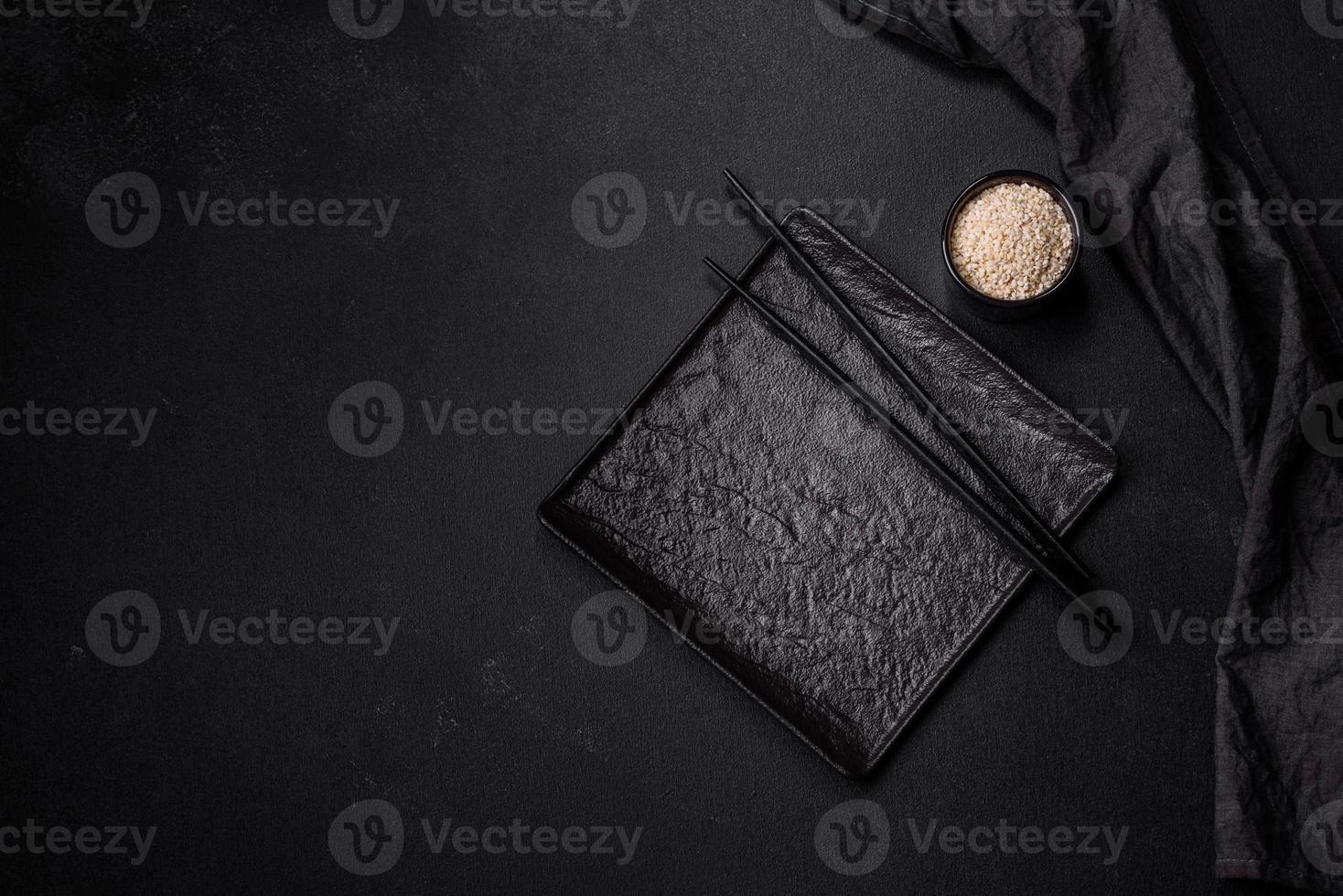 Empty plate with wooden sticks for Asian food on a dark concrete background photo