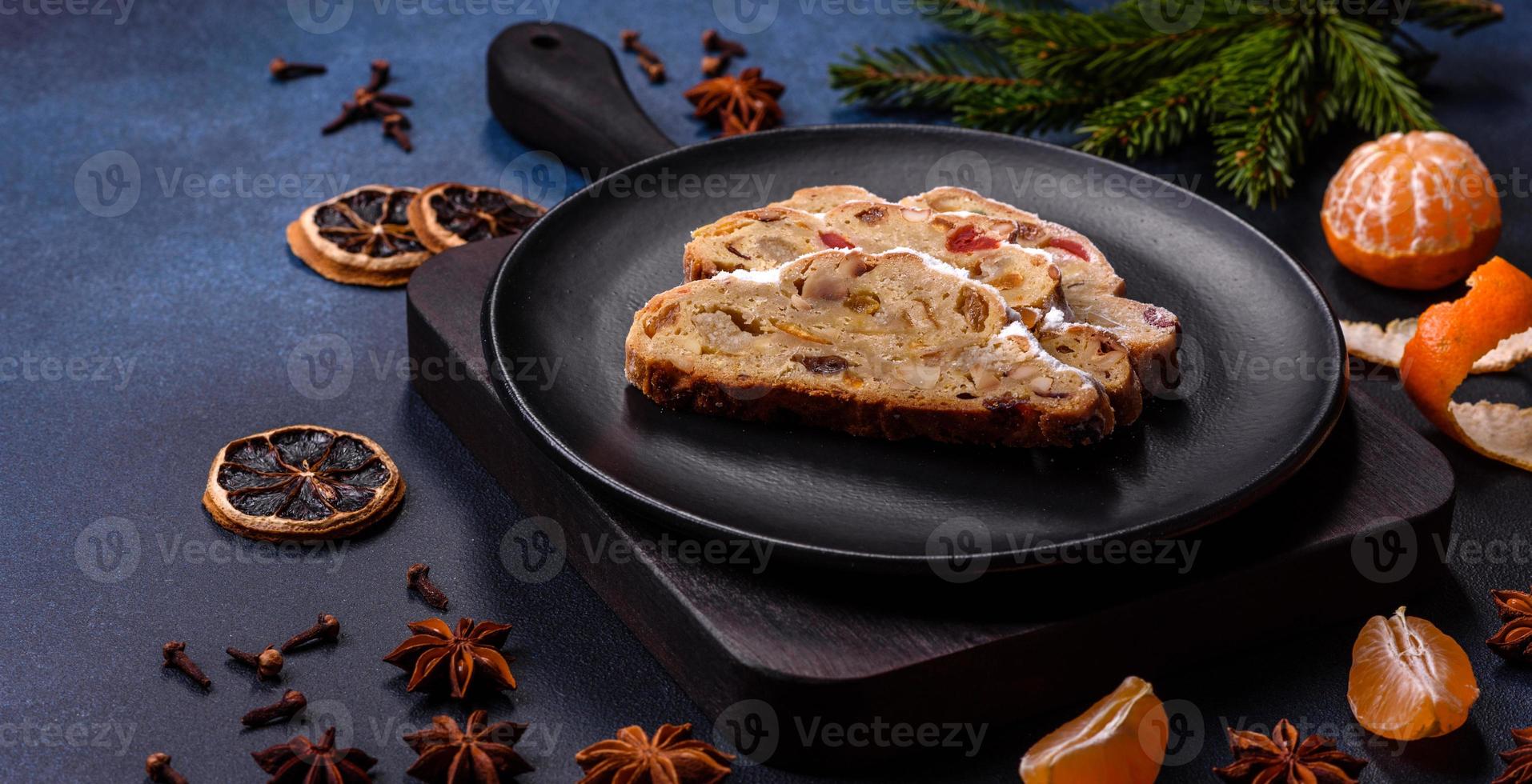 Delicious festive New Year's pie with candied fruits, marzipan and nuts on a dark concrete background photo