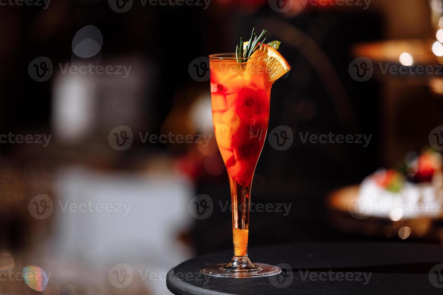Cóctel alcohólico exótico colorido fresco con naranja y romero en el escritorio del bar. sabroso refresco con frutas. enfoque selectivo foto