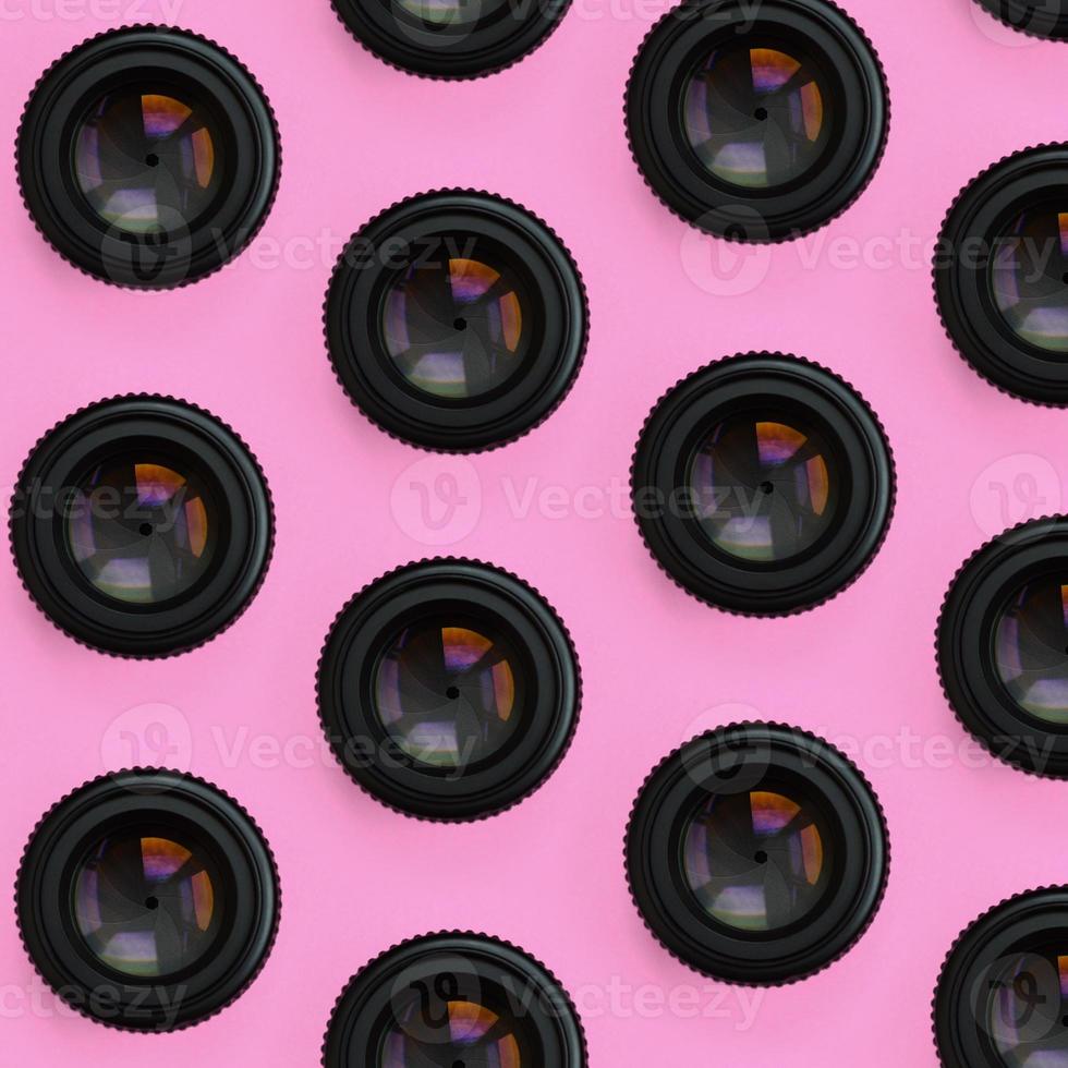 A few camera lenses with a closed aperture lie on texture background of fashion pastel pink color paper in minimal concept. Abstract trendy pattern photo