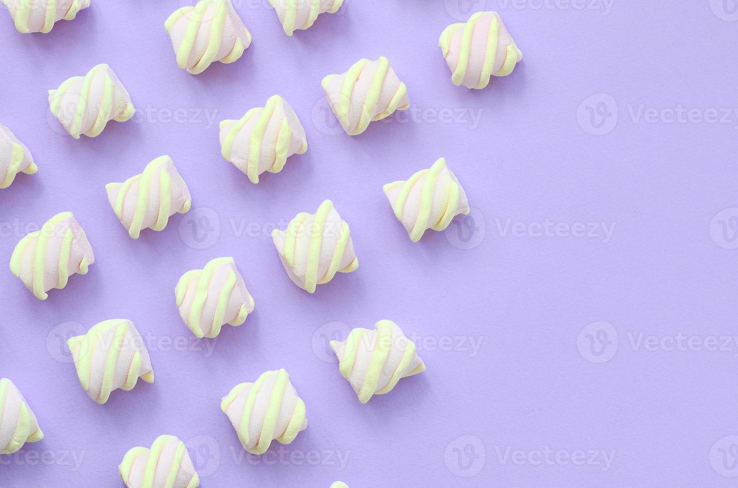 Colorful marshmallow laid out on violet paper background. pastel creative textures with copy space. minimal photo