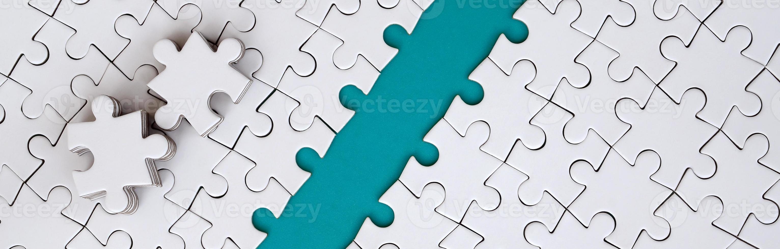 The blue path is laid on the platform of a white folded jigsaw puzzle. The missing elements of the puzzle are stacked nearby. Texture image with space for text photo