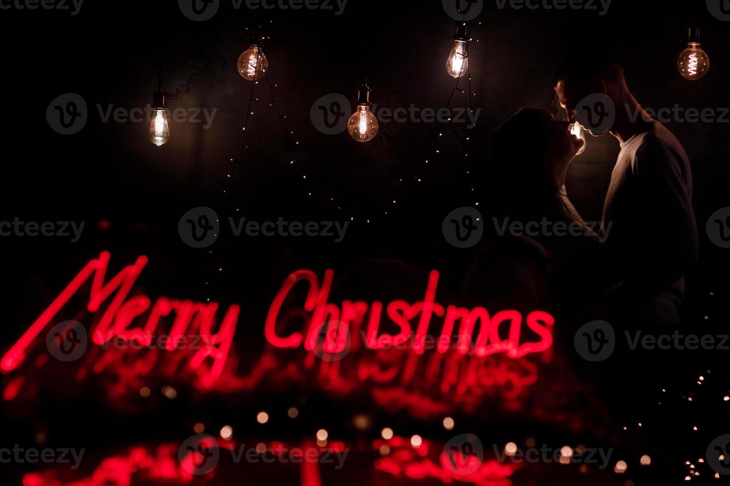 silhouette of a man and a woman on a background of lights in the dark, contour of the face, a kissing couple in the lights of the holiday, love and romance. New Year's Eve and Christmas. kiss under photo