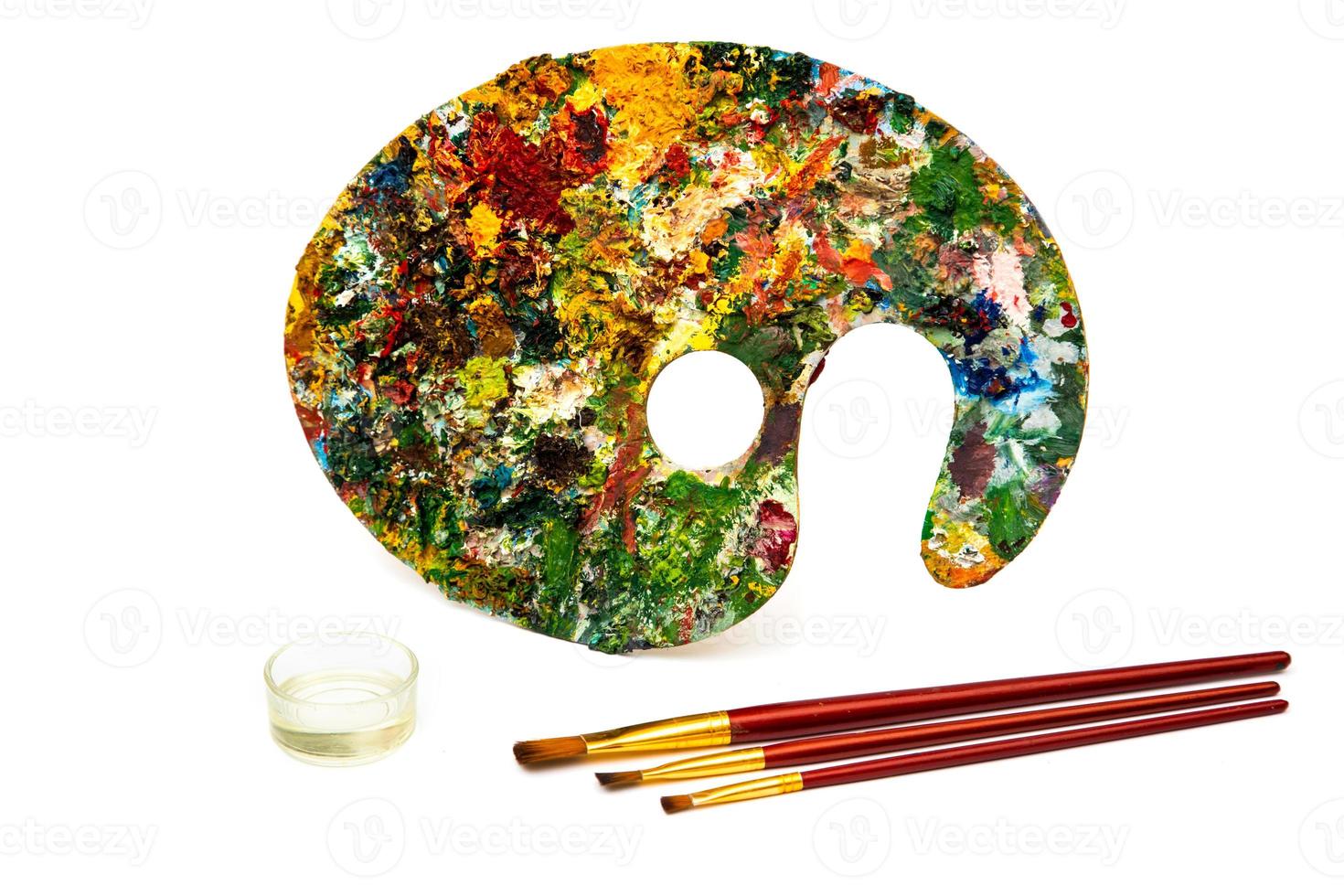 Palette with colorful paints. Colorful oil painting palette with a brush reaching in. Paint brushes and paints for drawing. photo