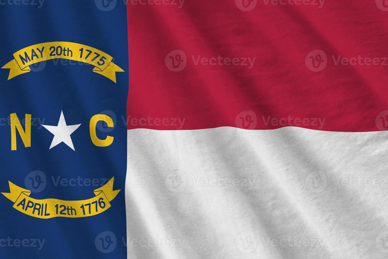 North Carolina US state flag with big folds waving close up under the studio light indoors. The official symbols and colors in banner photo
