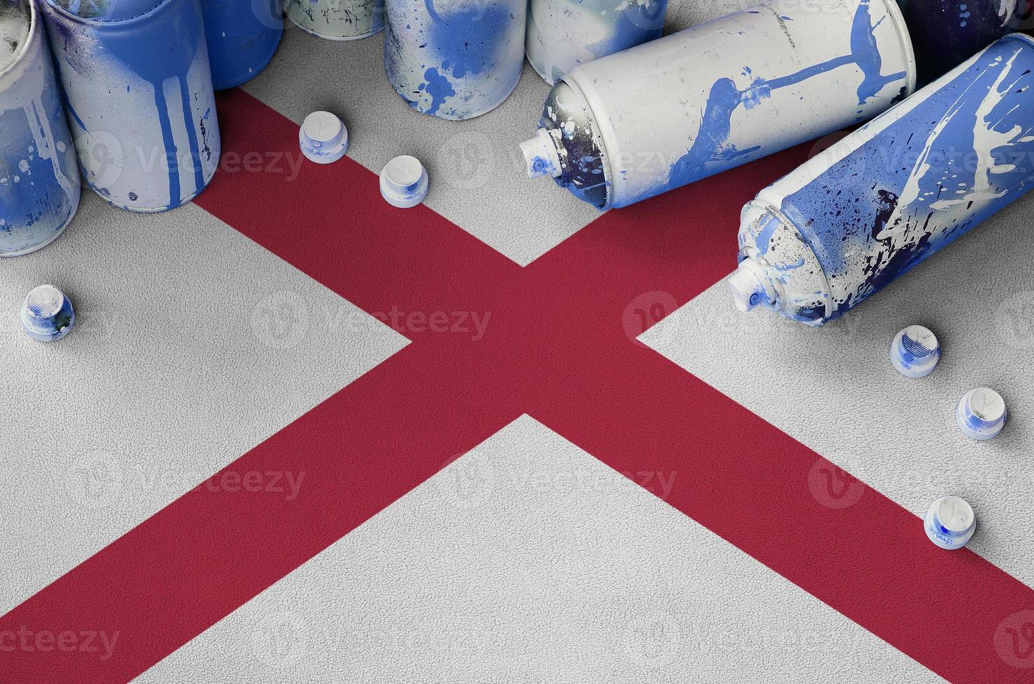 alabama bandera del estado de estados unidos y pocas latas de aerosol usadas para pintar graffiti. concepto de cultura de arte callejero foto