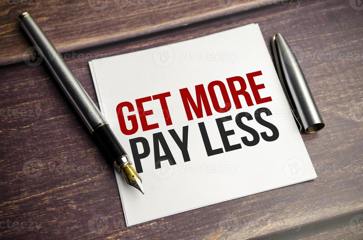 get more pay less . Text on business card with pen photo