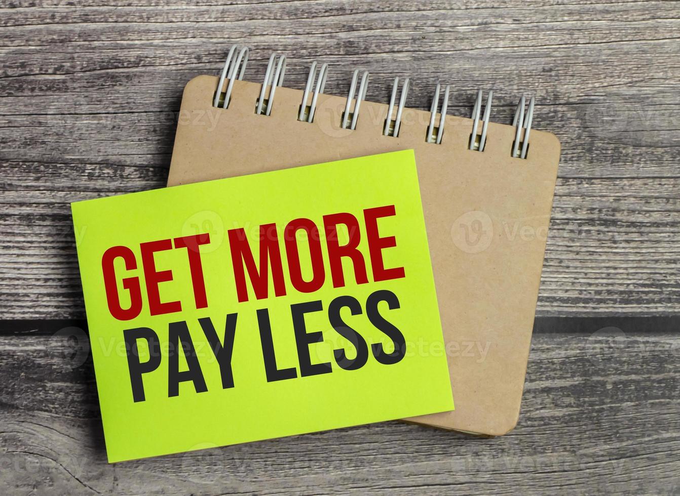 get more pay less. Text on green business card with pen photo