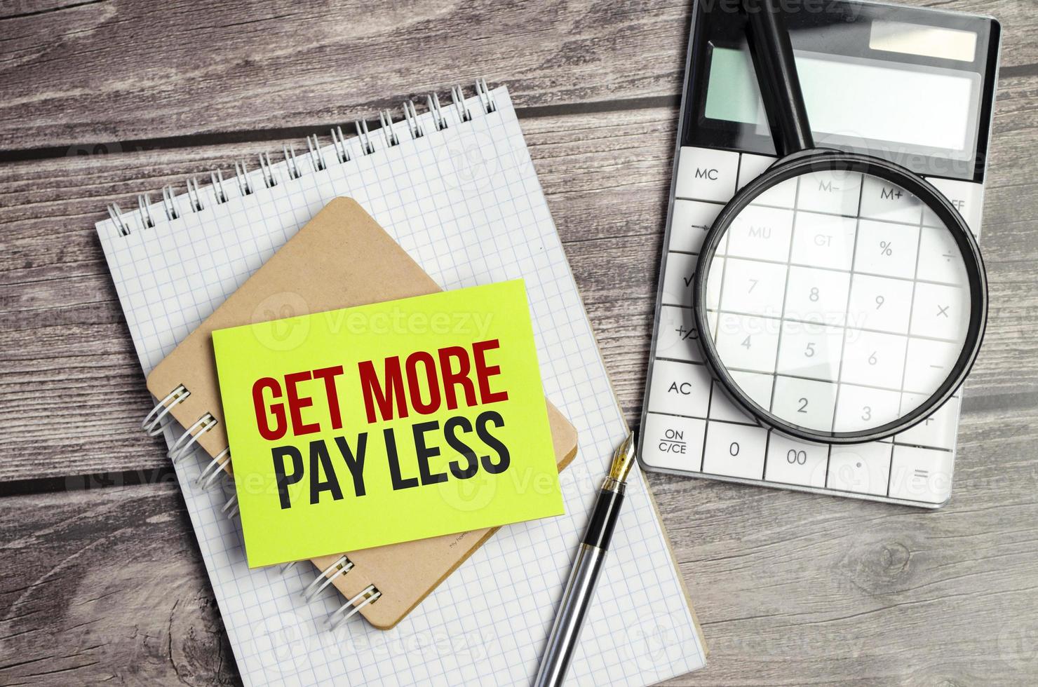 get more pay less Text on business paper on office table with office supplies photo