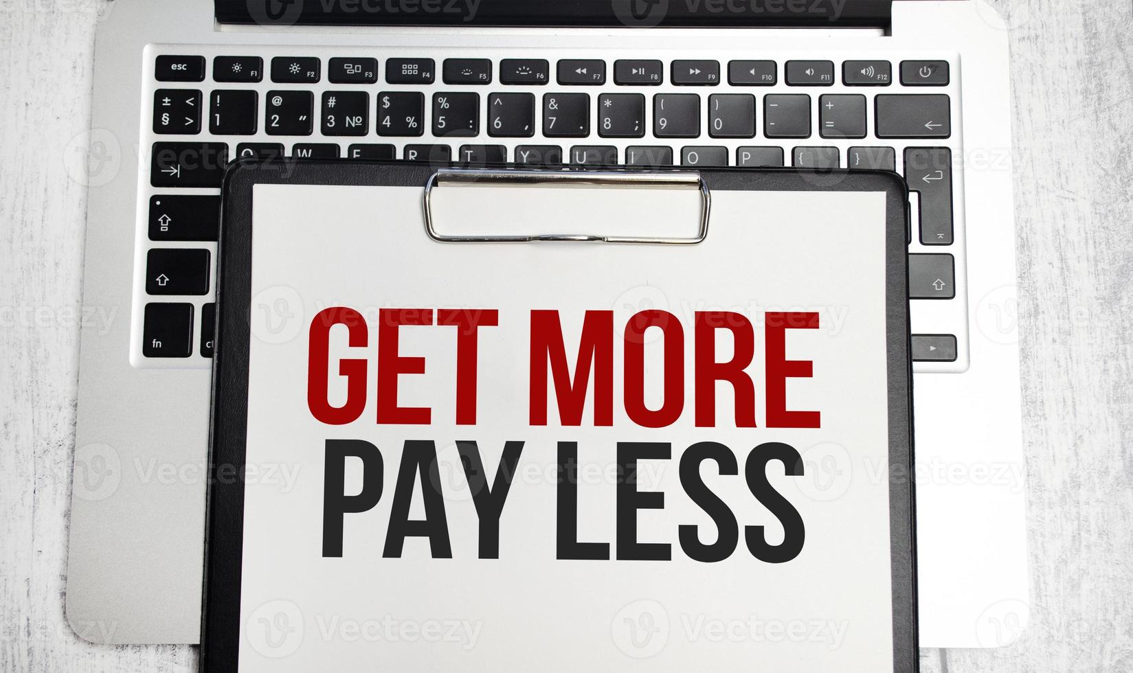 get more pay less words on paper tablet on laptop photo
