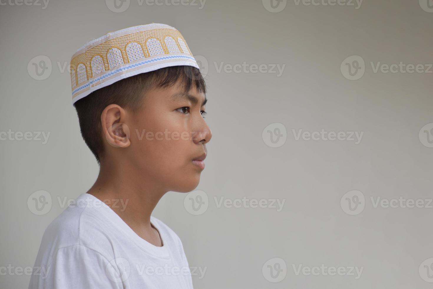 Portrait young southeast asian islamic or muslim boy in white shirt and hat, isolated on white, soft and selective focus. photo