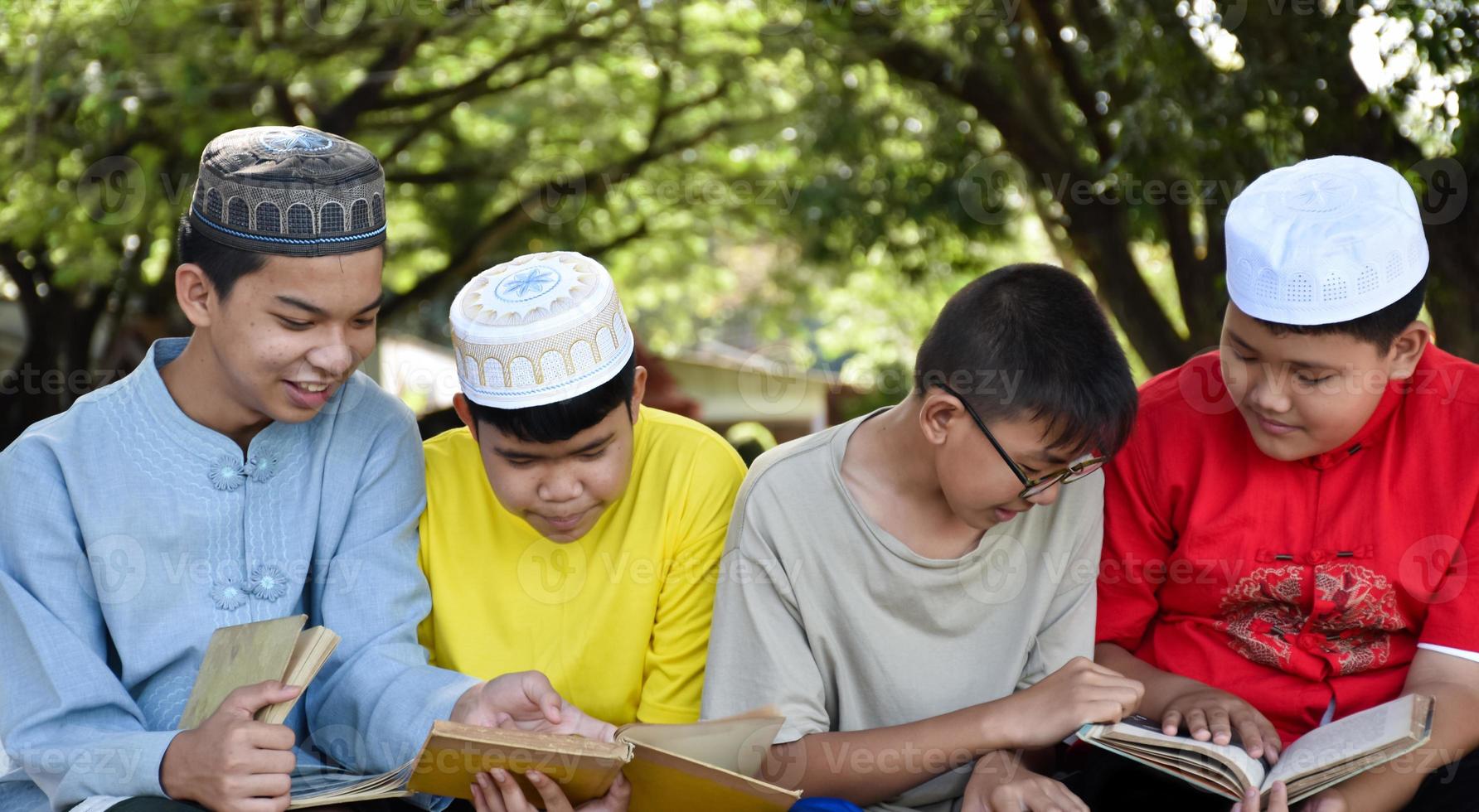 Group of muslim boys sit together under the tree in the school park, they also read, learn, talk, suggest and consult learning problems to each other, soft and selective focus. photo