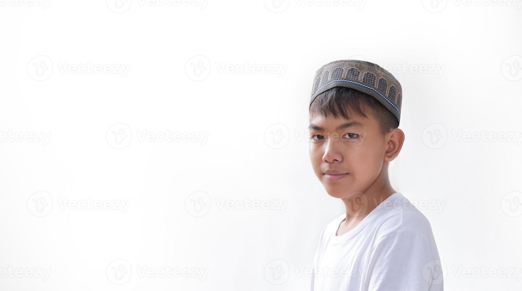 retrata a un joven islámico o musulmán del sudeste asiático con camisa blanca y sombrero, aislado en un enfoque blanco, suave y selectivo. foto