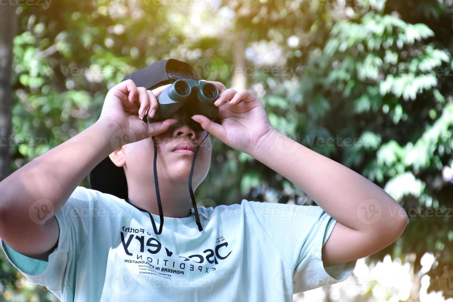 los niños del sudeste asiático están usando binoculares para observar aves en el bosque tropical, idea para aprender criaturas y animales salvajes fuera del aula. foto
