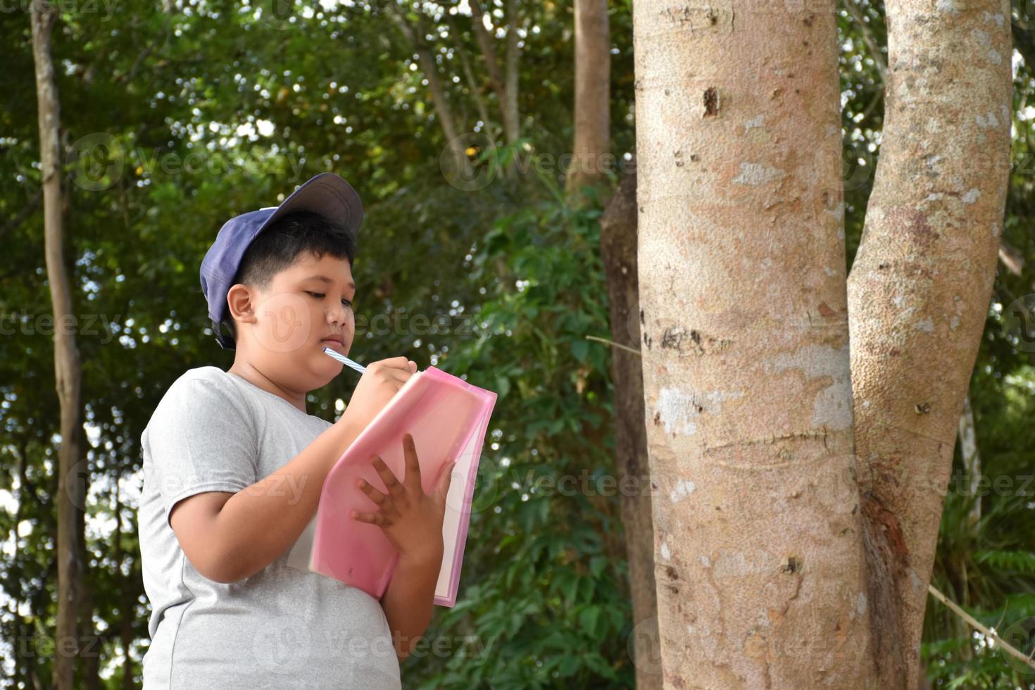 tres niños asiáticos están leyendo detalles de pájaros y van a usar binoculares para observar pájaros en los árboles durante el campamento de verano, idea para aprender criaturas y animales salvajes fuera del aula. foto