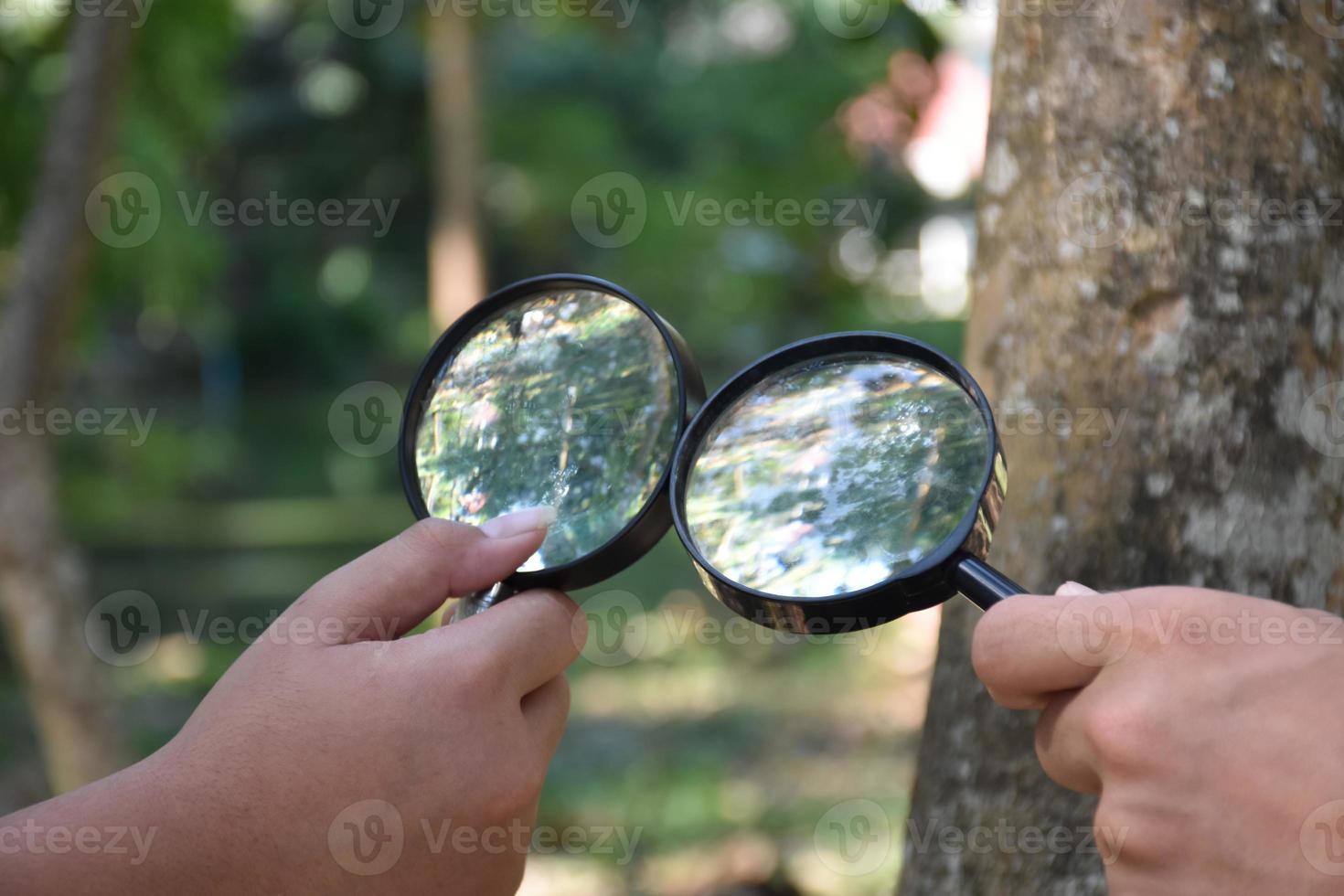 Two small black magnifying glasses holding in hands and were used during the summer camp to study microorganisms in plants and plants diseases. photo