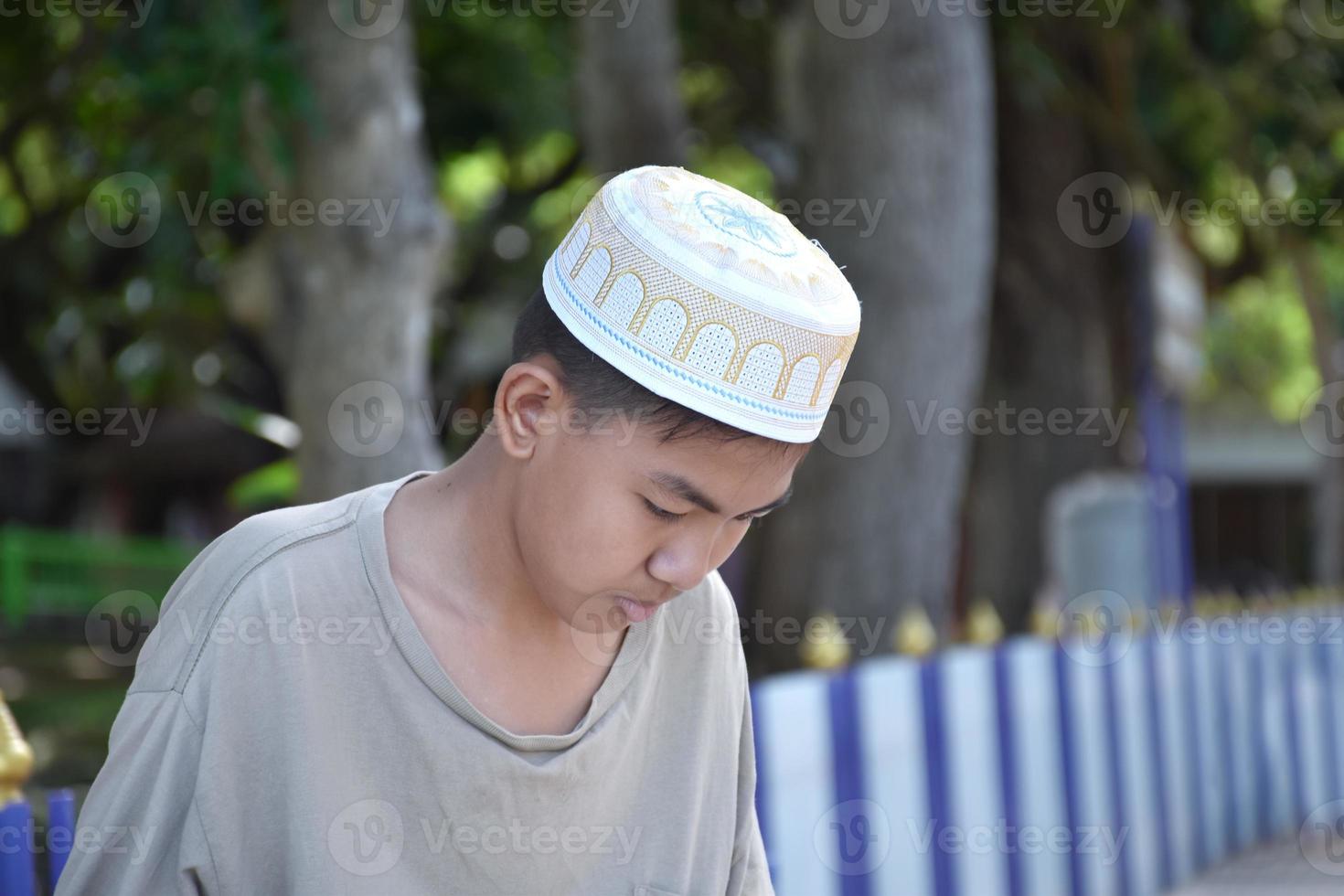 Portrait young southeast asian islamic or muslim boy in white shirt and hat, isolated on white, soft and selective focus. photo
