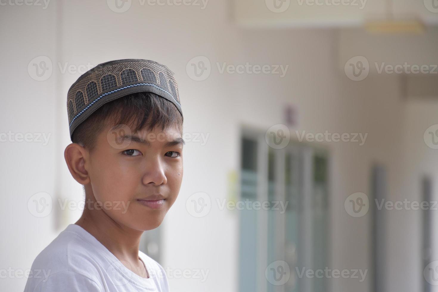 Portrait young southeast asian islamic or muslim boy in white shirt and hat, isolated on white, soft and selective focus. photo