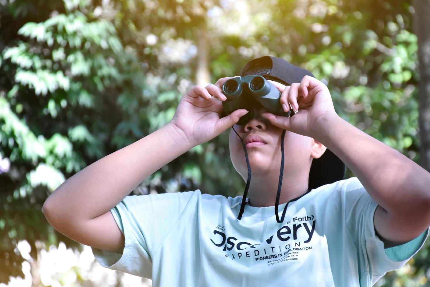 los niños del sudeste asiático están usando binoculares para observar aves en el bosque tropical, idea para aprender criaturas y animales salvajes fuera del aula. foto