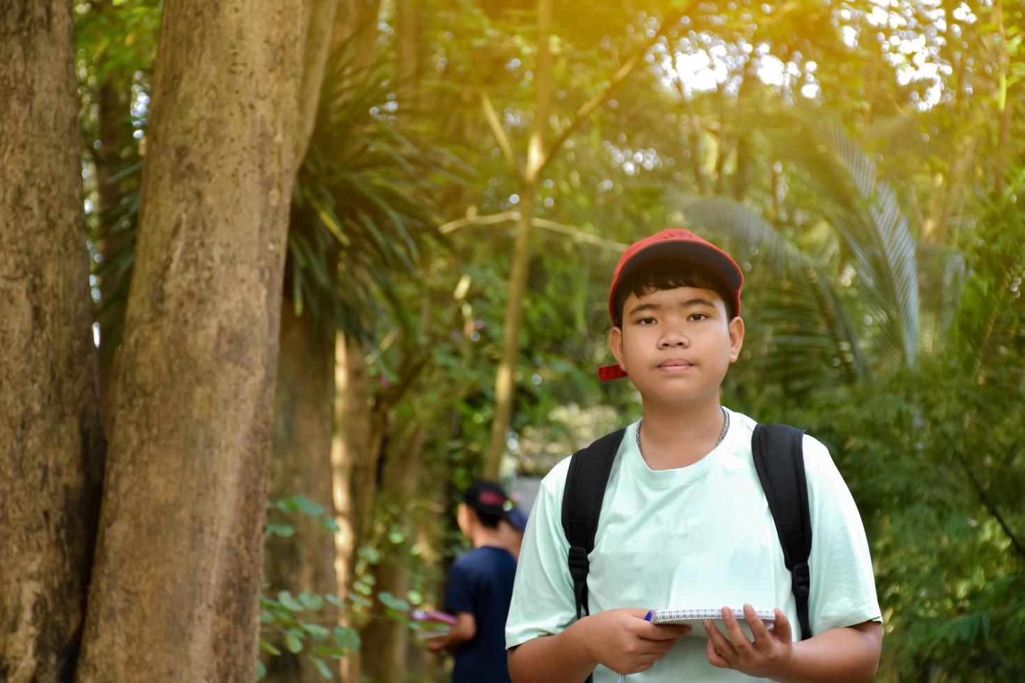 Three asian boys're reading birds details and going to use binoculars to watch birds on the trees during summer camp, idea for learning creatures and wildlife animals outside the classroom. photo