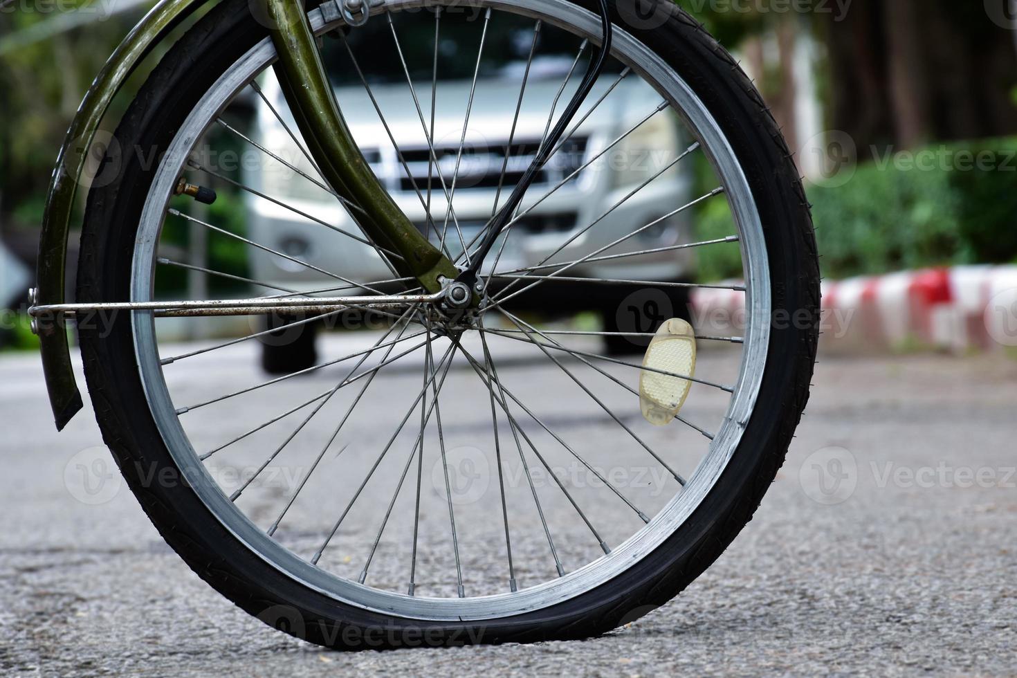 Rear wheel of bike which is flat and parked on the pavement beside the road. photo