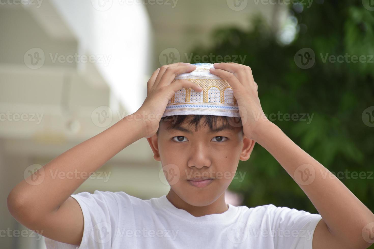 Portrait young southeast asian islamic or muslim boy in white shirt and hat, isolated on white, soft and selective focus. photo