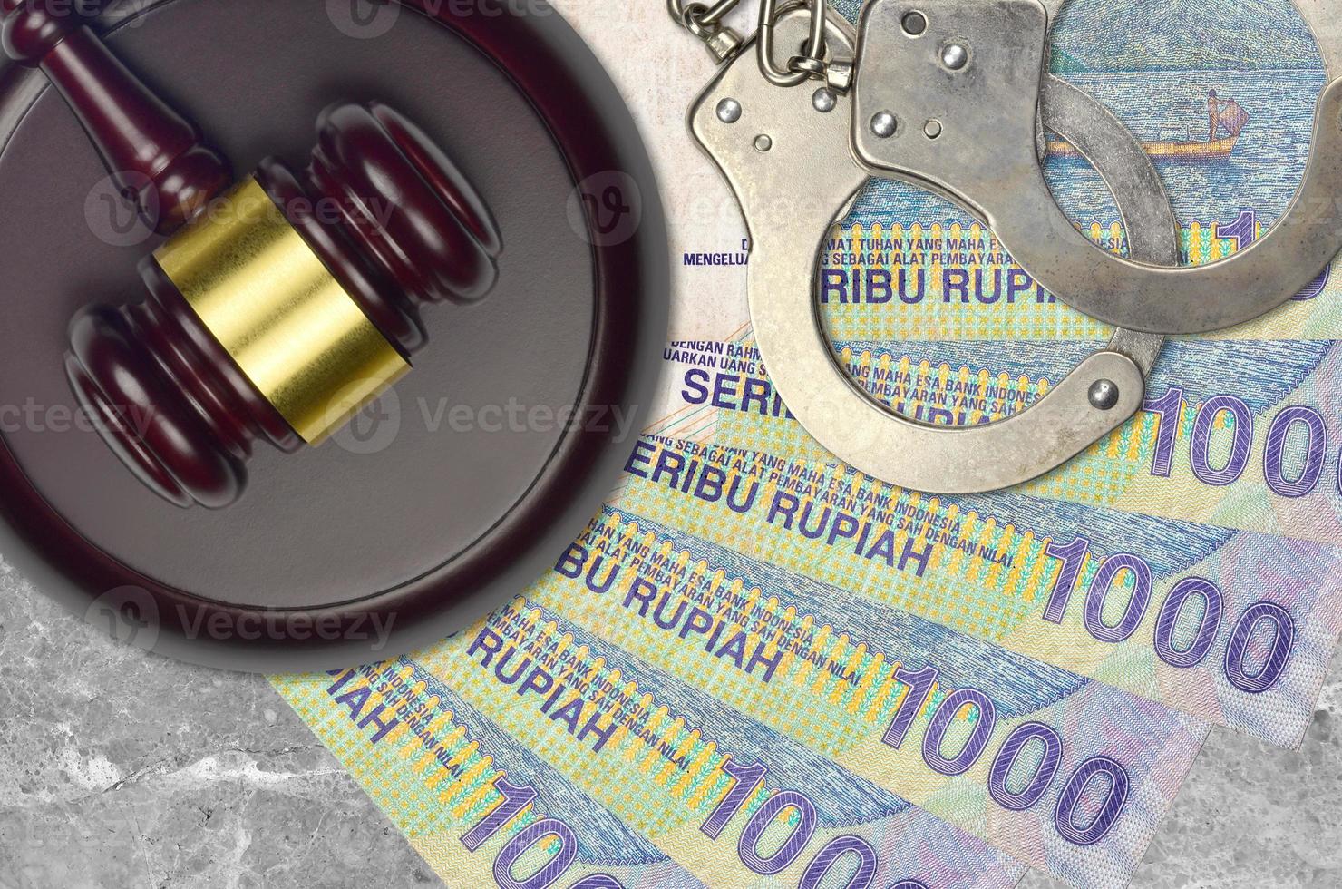1000 Indonesian rupiah bills and judge hammer with police handcuffs on court desk. Concept of judicial trial or bribery. Tax avoidance photo