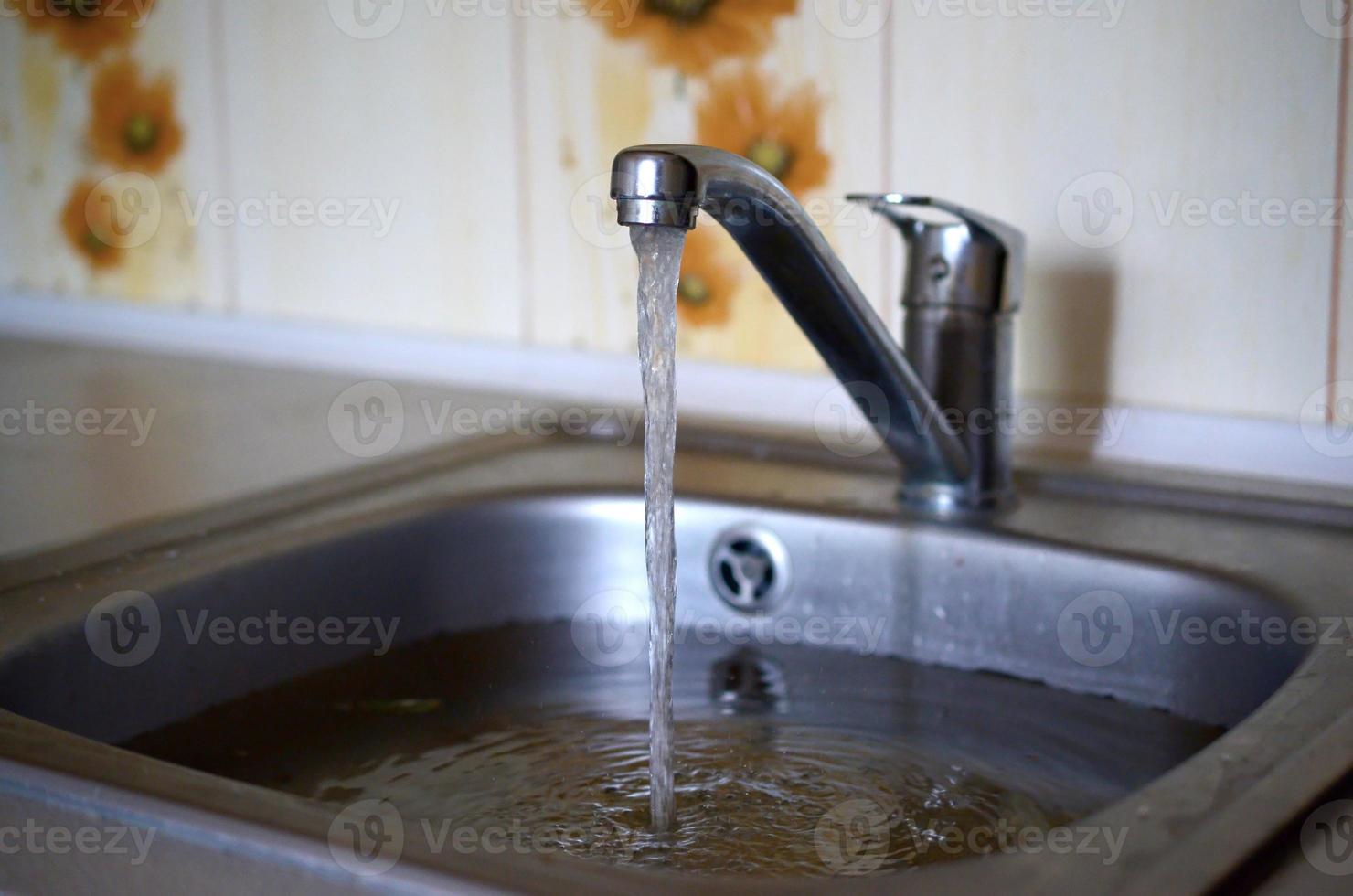 Stainless steel sink plug hole close up full of water and particles of food photo