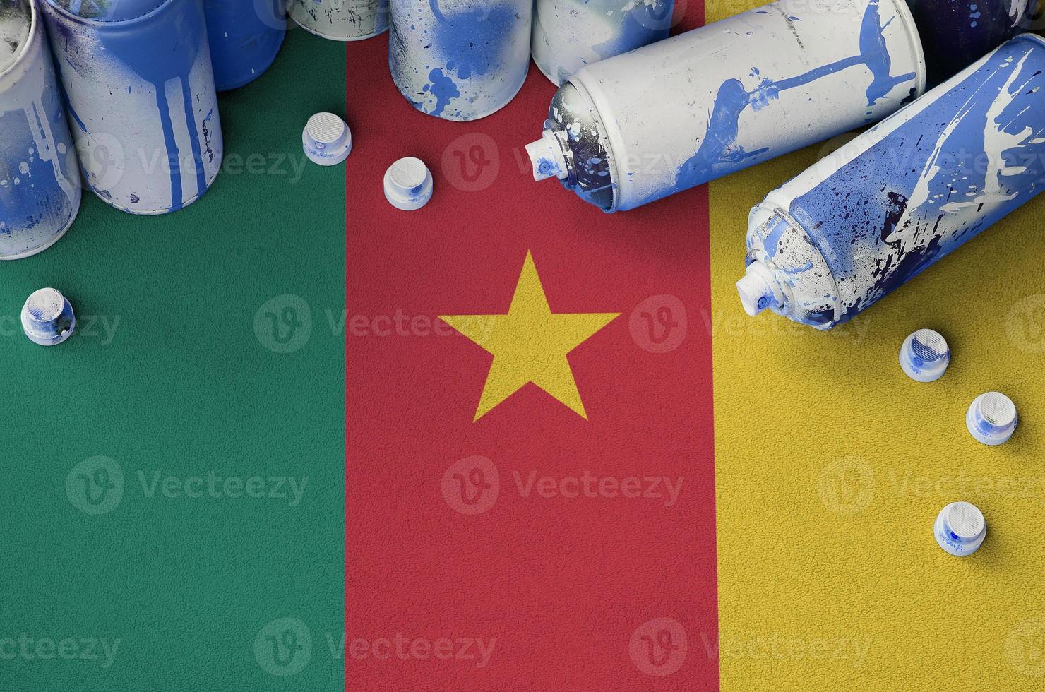 Cameroon flag and few used aerosol spray cans for graffiti painting. Street art culture concept photo