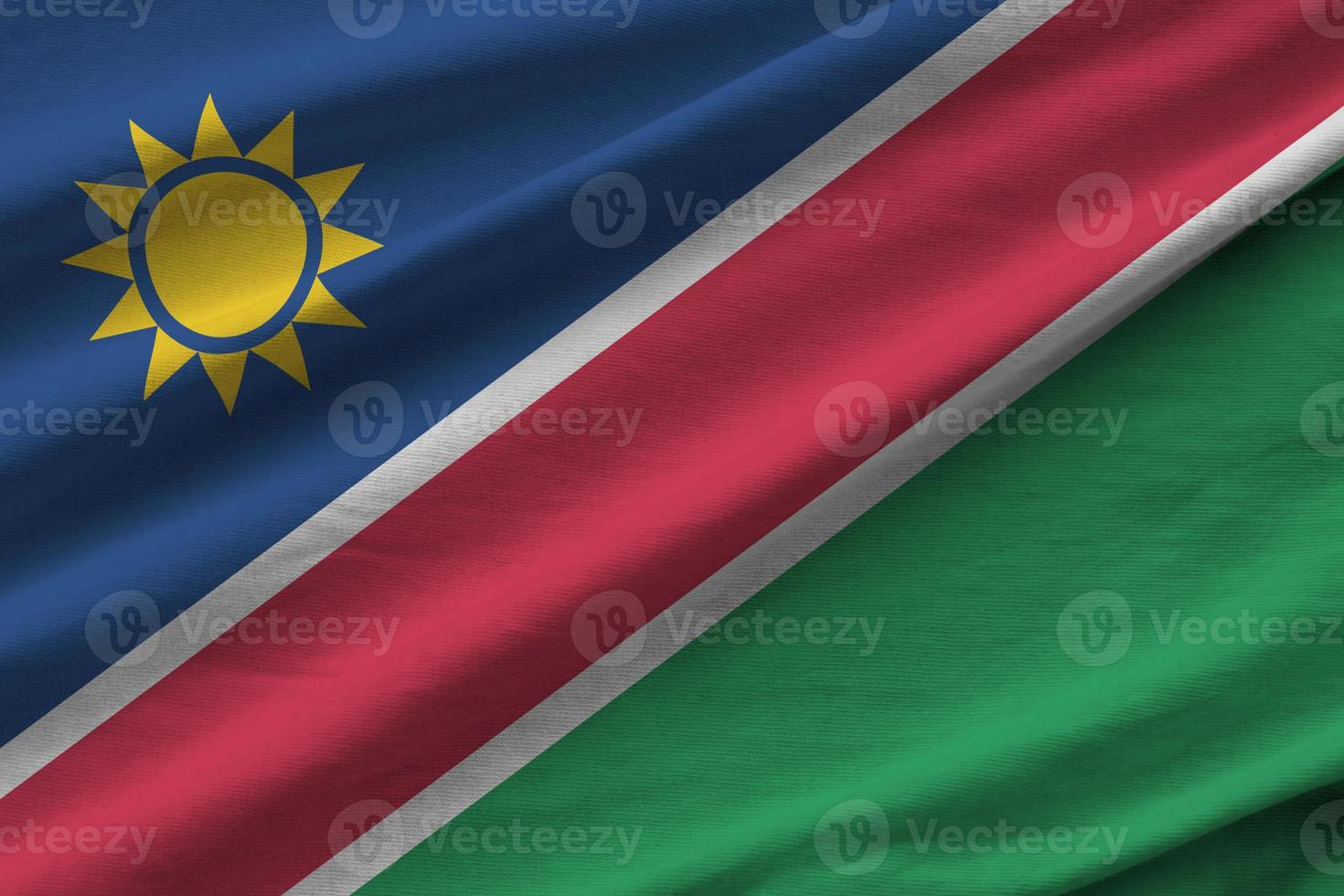 Namibia flag with big folds waving close up under the studio light indoors. The official symbols and colors in banner photo