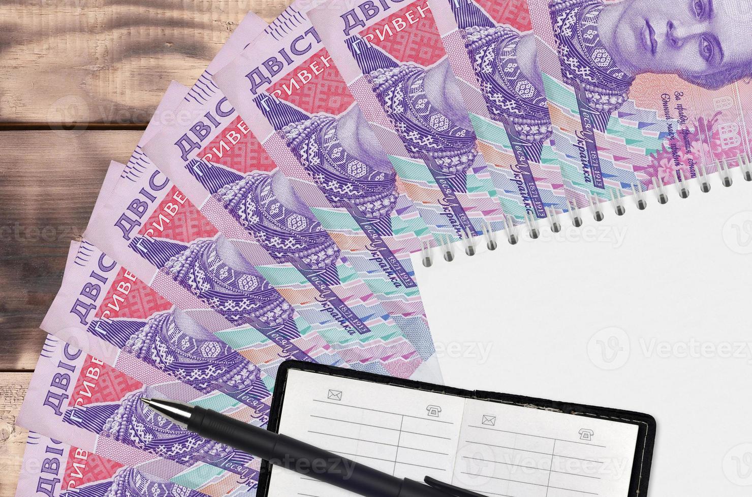 200 Ukrainian hryvnias bills fan and notepad with contact book and black pen. Concept of financial planning and business strategy photo