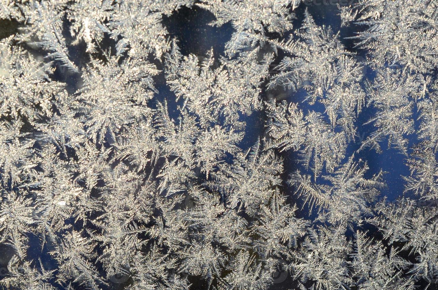 Snowflakes frost rime macro on window glass pane photo