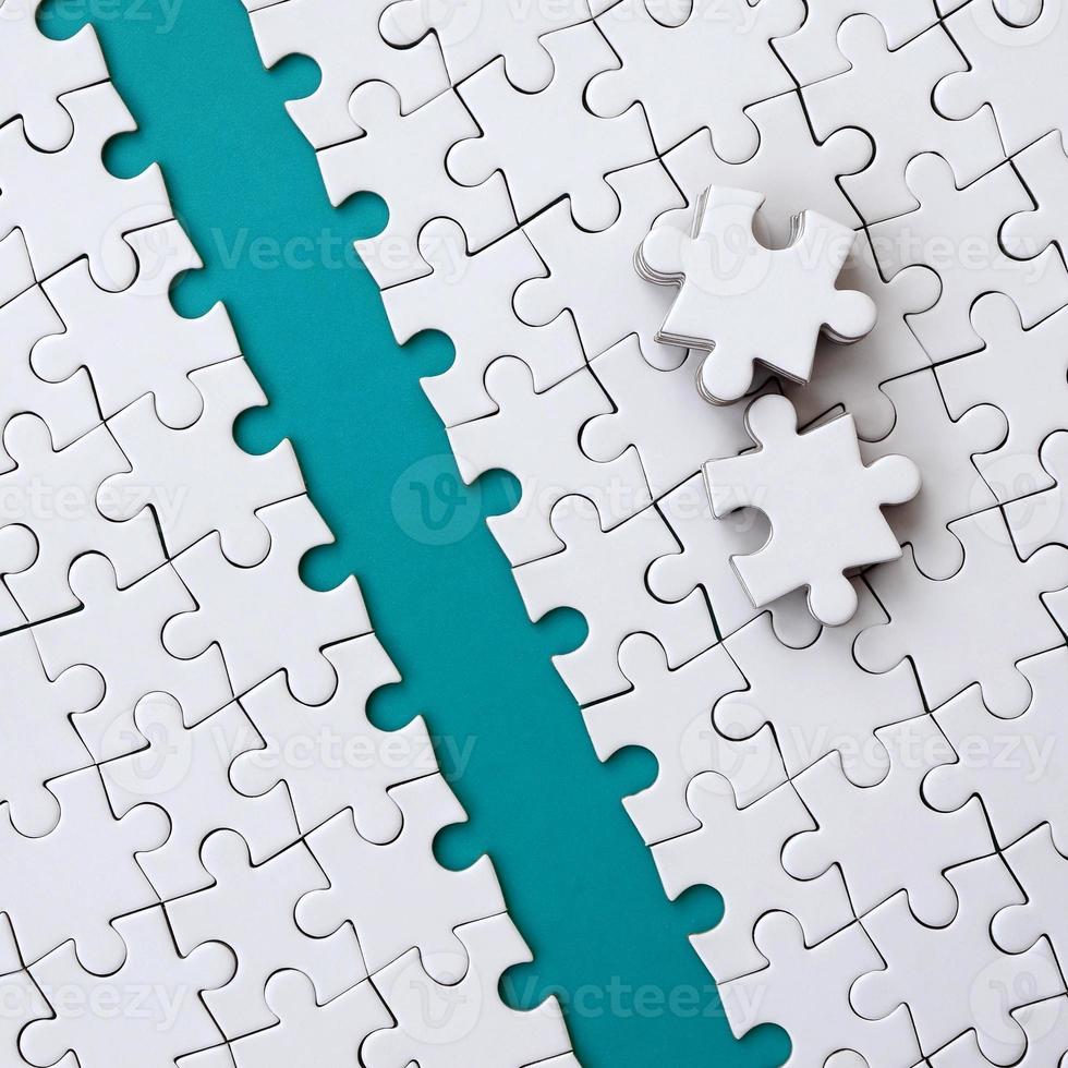 The blue path is laid on the platform of a white folded jigsaw puzzle. The missing elements of the puzzle are stacked nearby. Texture image with space for text photo