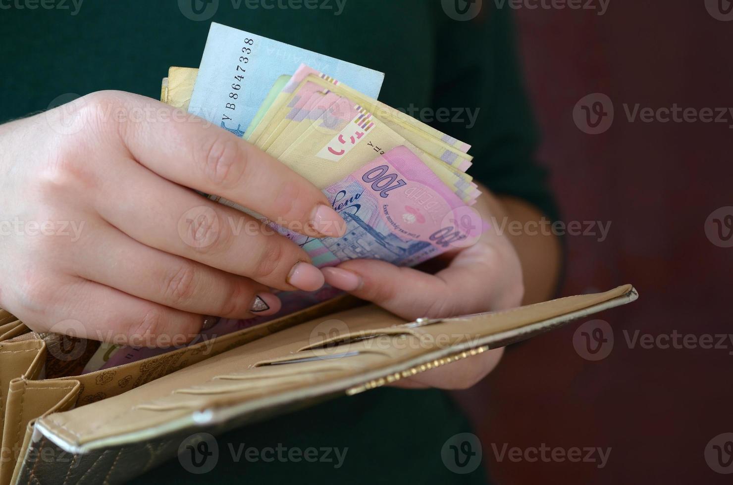 Female hands holding ukrainian hryvnia bills in small money pouch or wallet photo