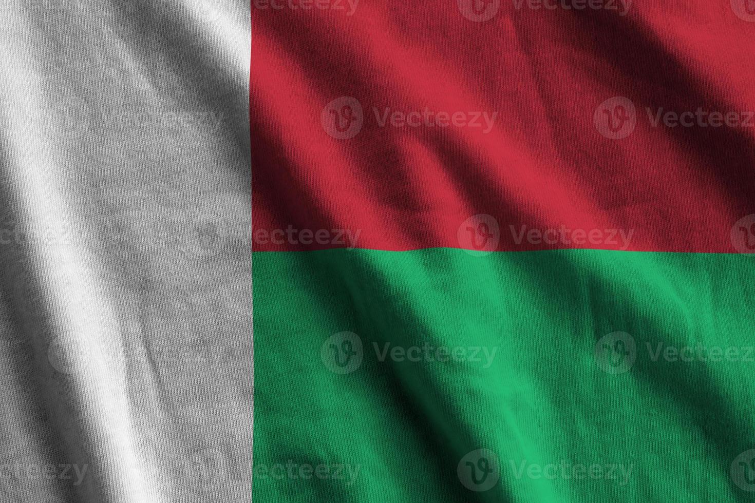 Madagascar flag with big folds waving close up under the studio light indoors. The official symbols and colors in banner photo
