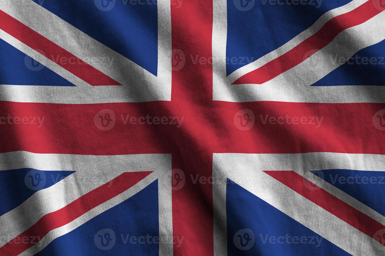 Great britain flag with big folds waving close up under the studio light indoors. The official symbols and colors in banner photo