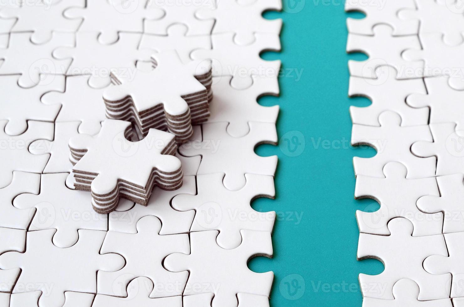 The blue path is laid on the platform of a white folded jigsaw puzzle. The missing elements of the puzzle are stacked nearby. Texture image with space for text photo