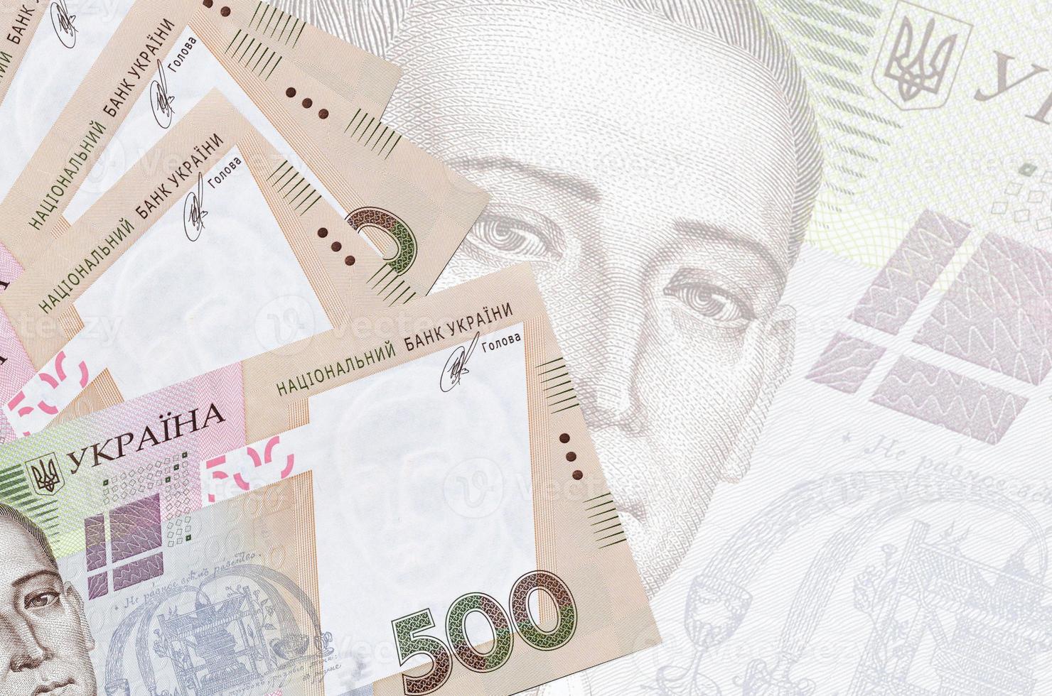 500 Ukrainian hryvnias bills lies in stack on background of big semi-transparent banknote. Abstract business background photo