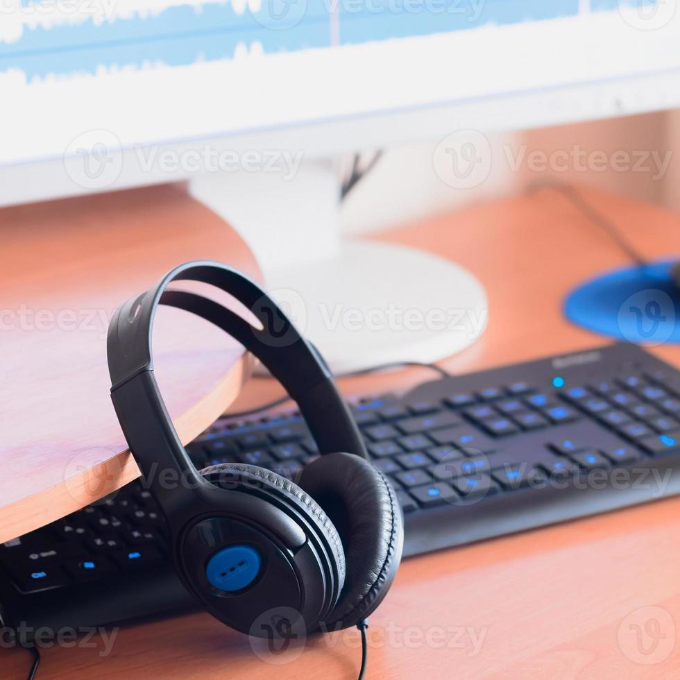 Big black headphones lie on the wooden desktop of the sound designer photo